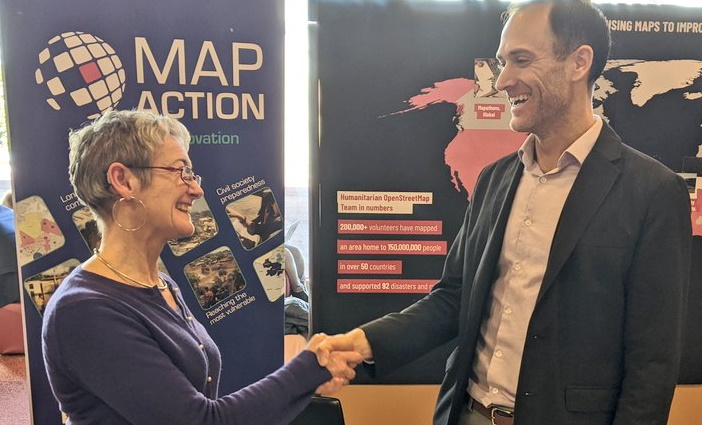 MapAction's LIz Hughes and Tyler Radford of HOT shaking hands and smiling at each other