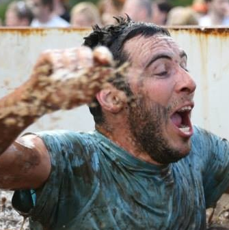 Hugh running through a chest-deep tank of cold muddy water on a Tough Mudder type race. 